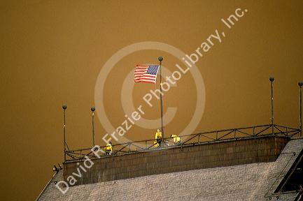 Firefighters with american flag atop the Old Faithful Inn as a firestorm passes at Yellowstone National Park, Wyoming in 1988.