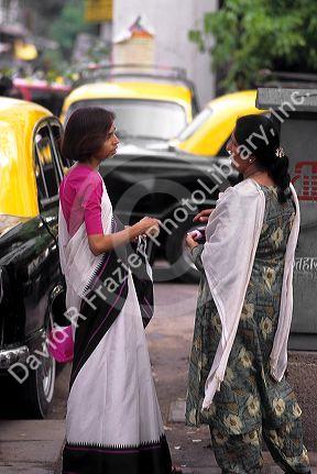 Indian women wearing saris talk on the street in Delhi, India.