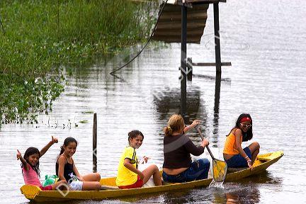 Brazilian girls in a canoe on the Arasa River in the Amazon jungle near Manaus, Brazil.