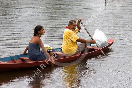 Brazilian man and woman in a canoe on the Arasa River in the Amazon jungle near Manaus, Brazil.