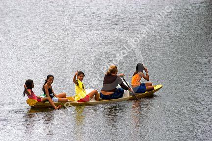 Brazilian girls riding in a canoe on the Arasa River in the Amazon jungle near Manaus, Brazil.