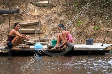 Brazilian girls washing clothes in the Arasa River in the Amazon jungle near Manaus, Brazil.