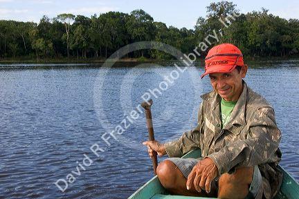 Brazilian man in a dugout canoe on the Arasa River in the Amazon jungle near Manaus, Brazil.