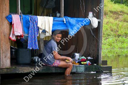 Brazilian girl washing clothes in the Arasa River in the Amazon jungle near Manaus, Brazil.