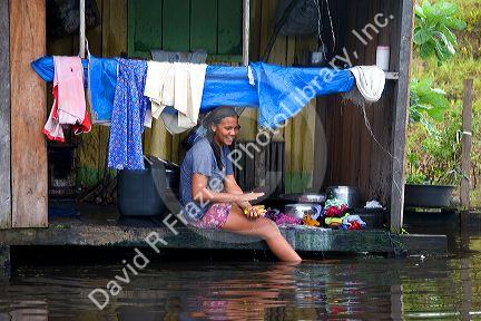 Brazilian girl washing clothes in the Arasa River in the Amazon jungle near Manaus, Brazil.