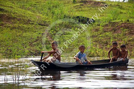 Brazilian boys in a dugout canoe on the Arasa River in the Amazon jungle near Manaus, Brazil.
