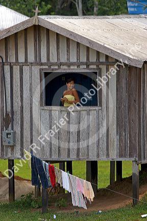 Brazilian girl in the window of her home in the Amazon jungle near Manaus, Brazil.