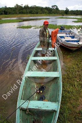 Brazilian man in a dugout canoe on the Arasa River in the Amazon jungle near Manaus, Brazil.