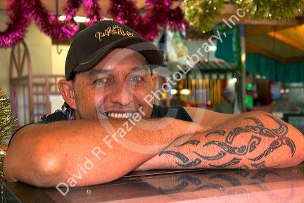 Tahitian man with traditional tatoo on his arm at a market in Papeete on the island of Tahiti.