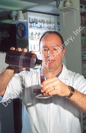 Pharmacist measuring cough syrup.