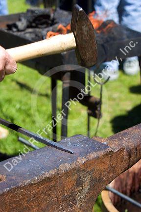 Blacksmith using a hammer to work with heated iron during a civil war reenactment near Boise, Idaho.