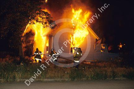 Firemen fighting a house fire with water.