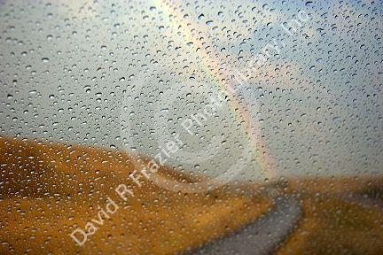 Rain drops on a car windshield with rainbow in the distance near Boise, Idaho.