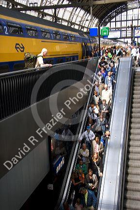 Passengers on escalators and trains at Amsterdam Central Station, Stationsplein, Amsterdam.