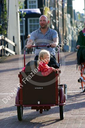 A child riding in a bicycle cart on the streets of Amsterdam, Netherlands.