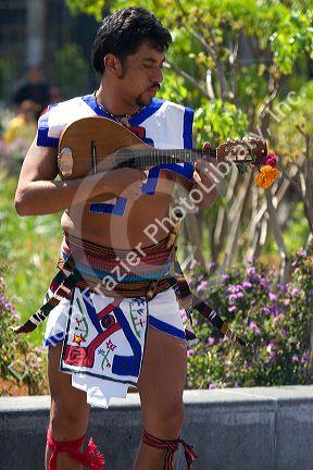 Aztec indian man in traditional dress playing the madolin during a celebration for the Day of the Dead in Mexico City, Mexico.
