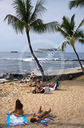 People on the beach with a cruise ship in the background near Kona on the Big Island of Hawaii.