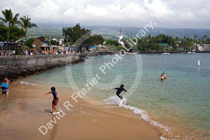 Children skimboarding at Kailua-Kona Bay on the Big Island of Hawaii.
