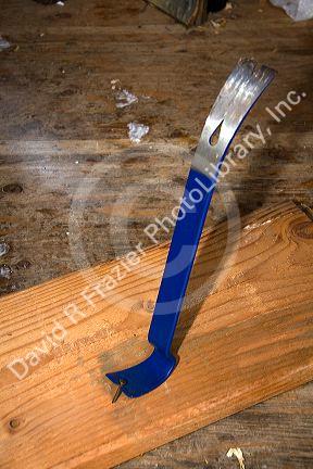 Flat pry bar pulling a nail out of a piece of lumber.