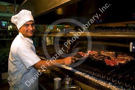 Argentine man grilling meat at a restaurant in Buenos Aires, Argentina.