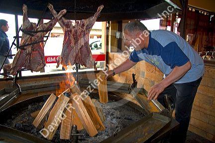 Man cooking meat over an open fire in a restaurant at Ushuaia on the island of Tierra del Fuego, Argentina.