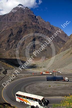 A bus and trucks drive on switchback roads in the Andes Mountain Range in Chile.