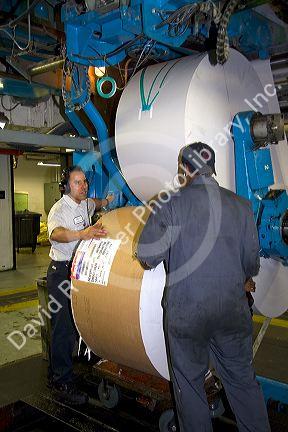 Pressmen loading large rolls of paper on to a rotary printing press for the Houston Chronicle in Houston, Texas.