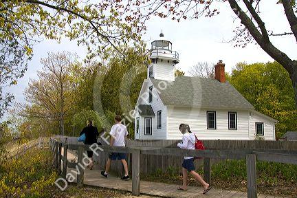 Visitors walk on wood walkways in front of the Mission Point Light, a lighthouse located at the end of Old Mission Point, Michigan.