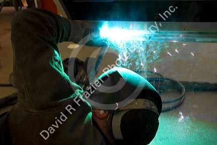 Worker Heliarc welding an aluminum truck chassis at Spartan Motors manufacturing plant in Charlotte, Michigan.
