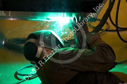 Worker Heliarc welding an aluminum truck chassis at Spartan Motors manufacturing plant in Charlotte, Michigan.