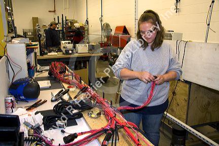 Female worker with wiring harness assembly at Spartan Motors truck chassis manufacturing in Charlotte, Michigan.