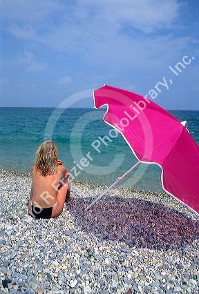 Woman sitting on the beach with an umbrella on the French Riviera.
