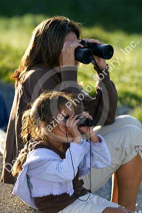 Hispanic mother and daughter viewing wildlife with binoculars in Yellowstone National Park, Wyoming. MR