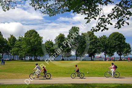 Bicyclists ride along the Seawall path in Stanley Park at Vancouver, British Columbia, Canada.