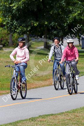 Bicyclists ride along the Seawall path in Stanley Park at Vancouver, British Columbia, Canada.