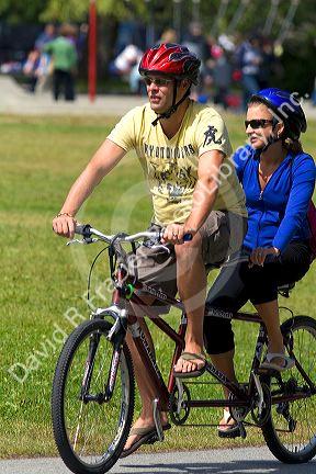 Couple riding a tandem bicycle along the Seawall path in Stanley Park at Vancouver, British Columbia, Canada.