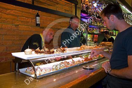 Customer choosing pinxtos at a tavern in the city of Bilbao, Biscay, Basque Country, northern Spain.