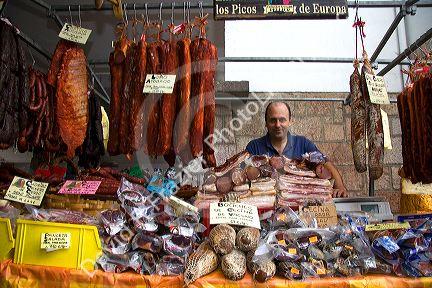 Vendor selling cured meats at an outdoor market in the town of Cangas de Onis, Asturias, northern Spain.