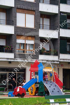 Children use playground equipment in front of an apartment housing unit in Guernica in the province of Biscay, Basque Country, Northern Spain.