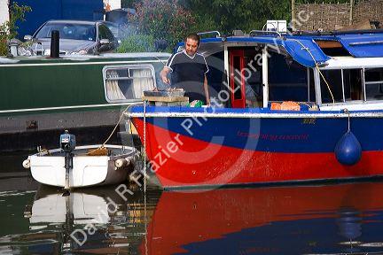 Man cooking on a narrowboat moored in the River Avon at Stratford-upon-Avon, Warwickshire, England.