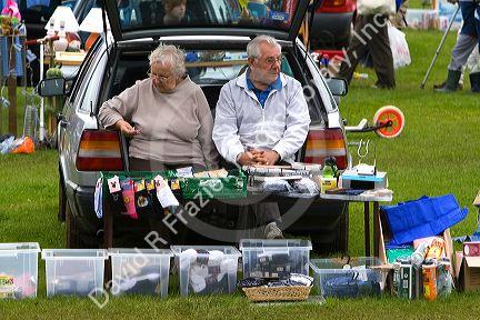 Elderly couple selling items at a car boot sale in the market town of Banbury, Oxfordshire, England.