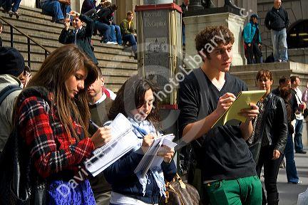 Students taking notes in front of the Fereal Hall located on 26 Wall Street in New York City, New York, USA.