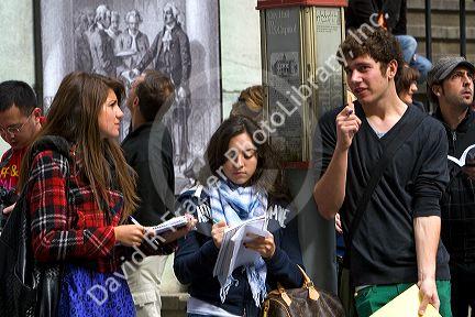 Students taking notes in front of the Federal Hall on 26 Wall Street in New York City, New York, USA.