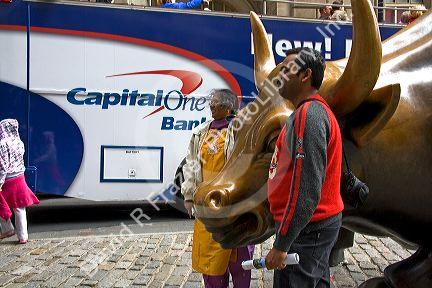 Tourists having their photo taken with the Wall Street Bull in Bowling Green park near Wall Street, New York City, New York, USA.