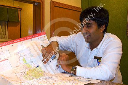 Hotel desk clerk using a map to give directions in the town of Ashland, New Hampshire, USA.