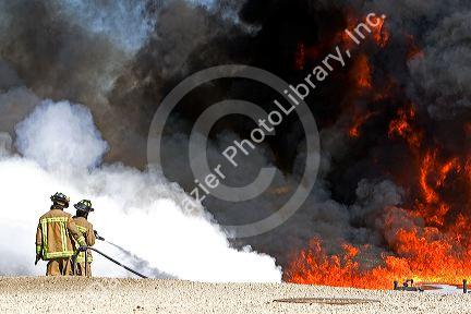 Firefighters using fire retardant foam to put out a jet fuel fire at an airport training facility in Boise, Idaho, USA.