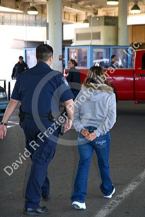 U.S. Customs and Immigration agent escorting a suspected illegal alien handcuffed at the United States port of entry at the Tijuana, Baja California, Mexico/San Diego, California border crossing.