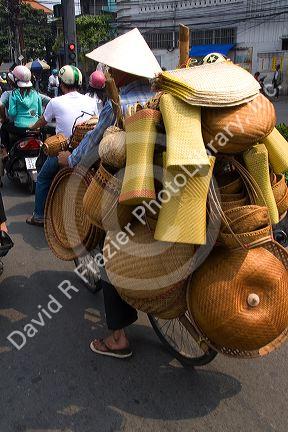 Vietnamese man riding a bicycle with many baskets in Ho Chi Minh City, Vietnam.