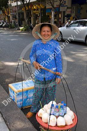 Vietnamese woman selling coconuts and bottled water on the street in Ho Chi Minh City, Vietnam.