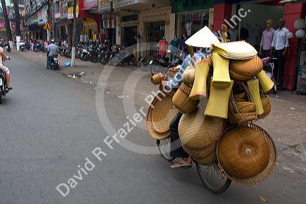 Vietnamese man riding a bicycle with many baskets in Ho Chi Minh City, Vietnam.